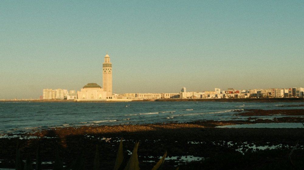 The Hassan II Mosque in Casablanca standing on its ocean-front platform, minaret rising against an evening sky beside the Atlantic