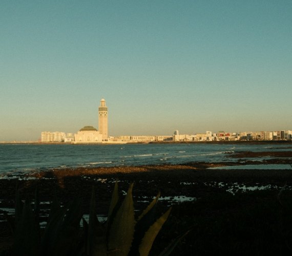 The Hassan II Mosque in Casablanca standing on its ocean-front platform, minaret rising against an evening sky beside the Atlantic