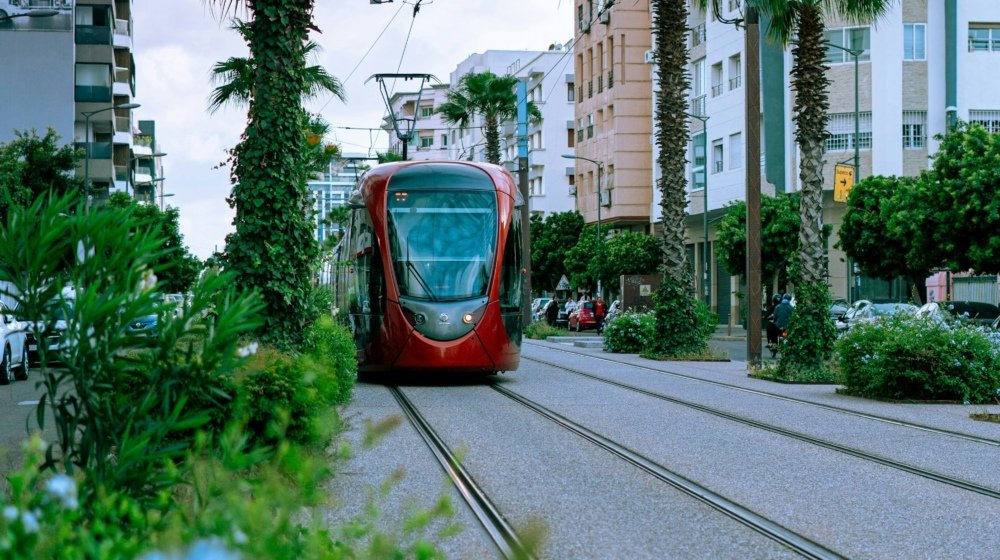 A red tram running along tracks through central Casablanca with tall modern buildings lining the street