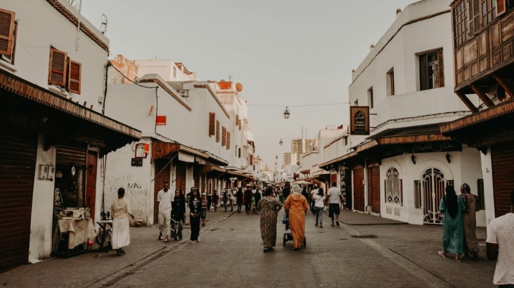 A group of people walking together down a Rabat street lined with tall buildings