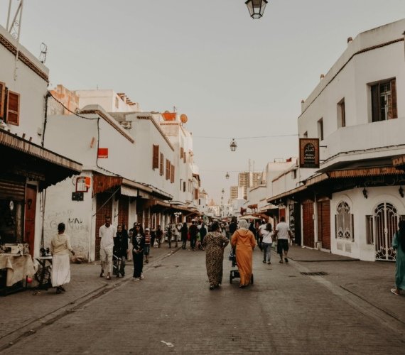 A group of people walking together down a Rabat street lined with tall buildings