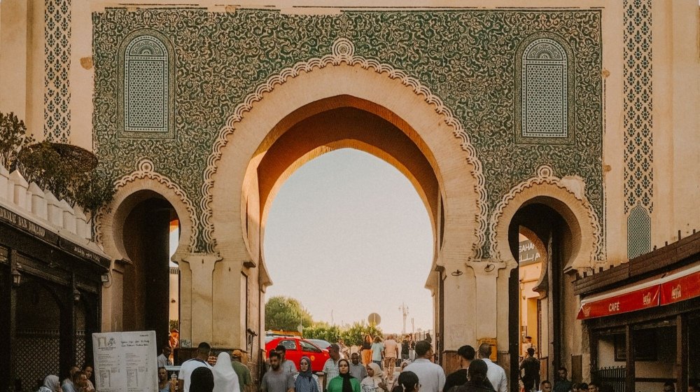 Visitors walking through the tiled Blue Gate archway into the old medina of Fez