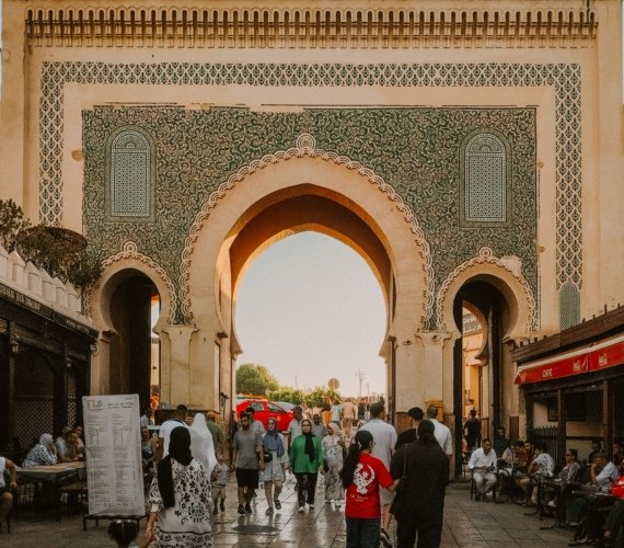Visitors walking through the tiled Blue Gate archway into the old medina of Fez
