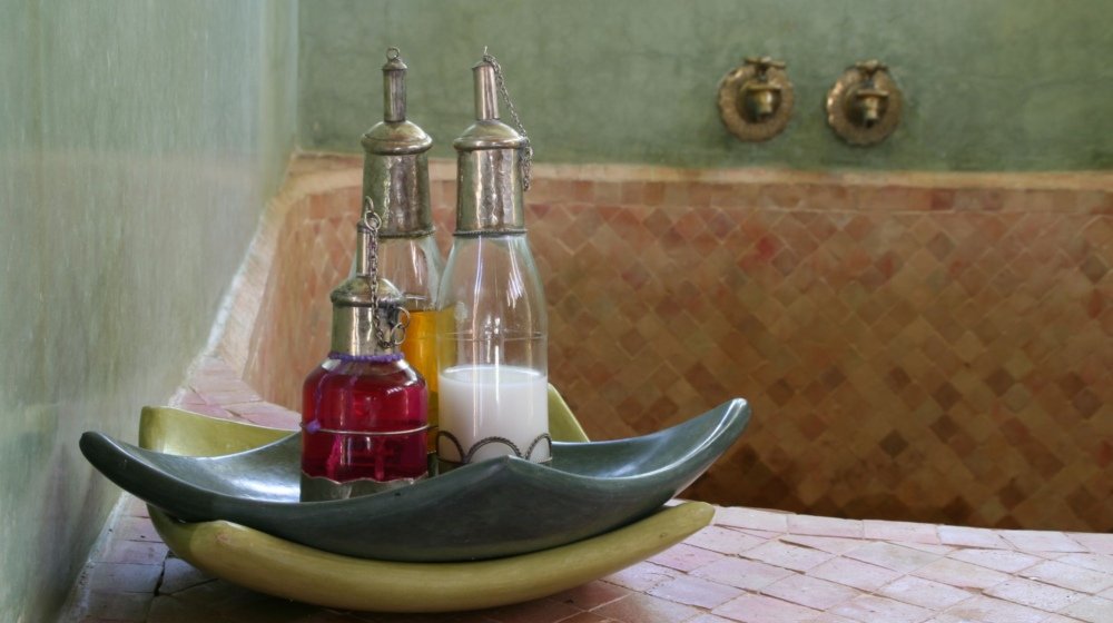 Interior of a traditional Moroccan hammam with tiled walls and bottles of massage and treatment oils set out ready for a bath ritual