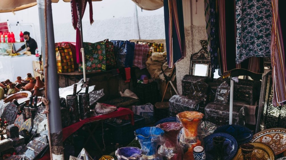 A Casablanca souk stall stacked with colourful glazed Moroccan pottery and traditional textiles on open display