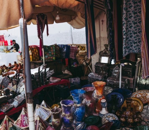 A Casablanca souk stall stacked with colourful glazed Moroccan pottery and traditional textiles on open display