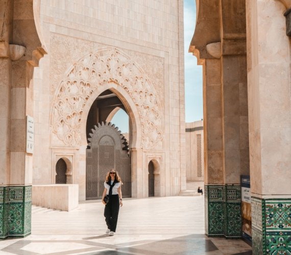 A visitor walking through the intricately carved and tiled arcades of the Hassan II Mosque in Casablanca