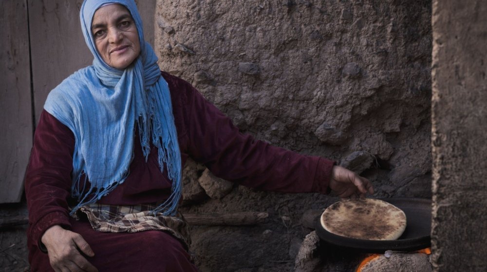 Moroccan woman baking traditional flatbread over an open stove in the Ourika Valley near Marrakech