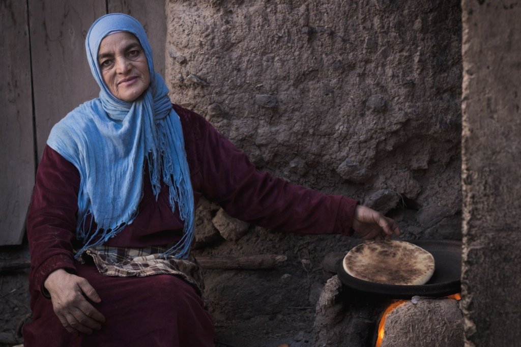 Moroccan woman baking traditional flatbread over an open stove in the Ourika Valley near Marrakech