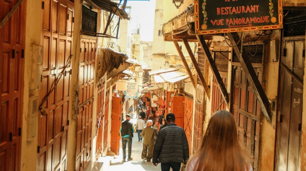 Visitors walking through a narrow alleyway in the medina of Fes, Morocco