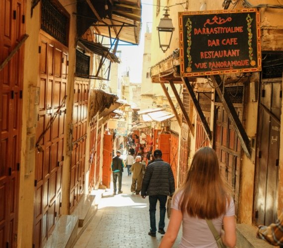 Visitors walking through a narrow alleyway in the medina of Fes, Morocco