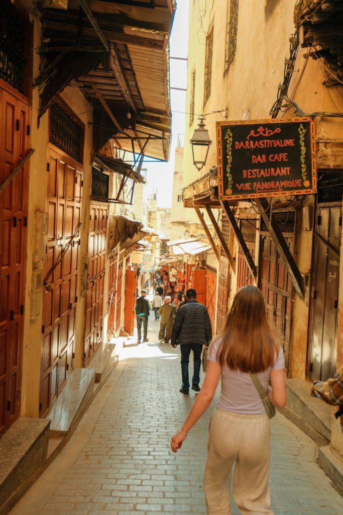 Visitors walking through a narrow alleyway in the medina of Fes, Morocco