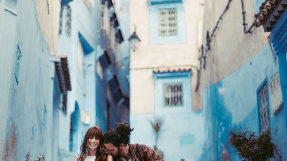 A couple standing in a blue-painted alleyway in Chefchaouen, Morocco