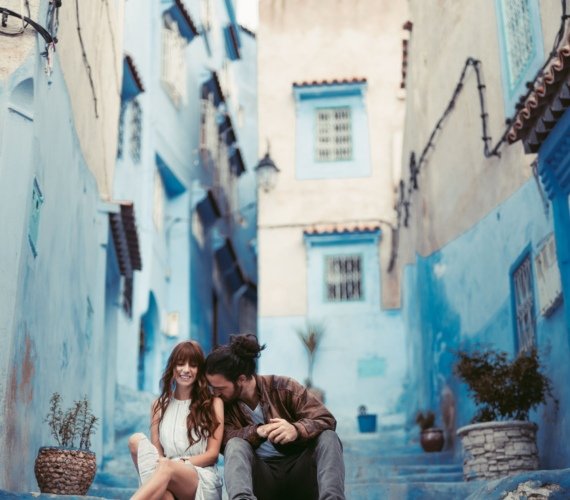 A couple standing in a blue-painted alleyway in Chefchaouen, Morocco