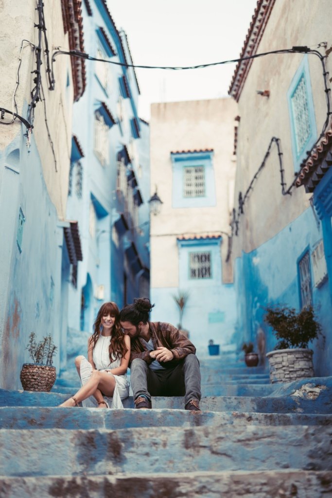 A couple standing in a blue-painted alleyway in Chefchaouen, Morocco