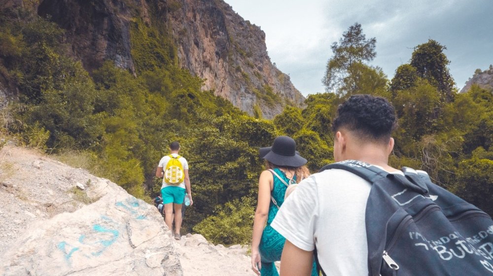A group of hikers on a rocky trail through the green Akchour gorge in Morocco's Rif Mountains