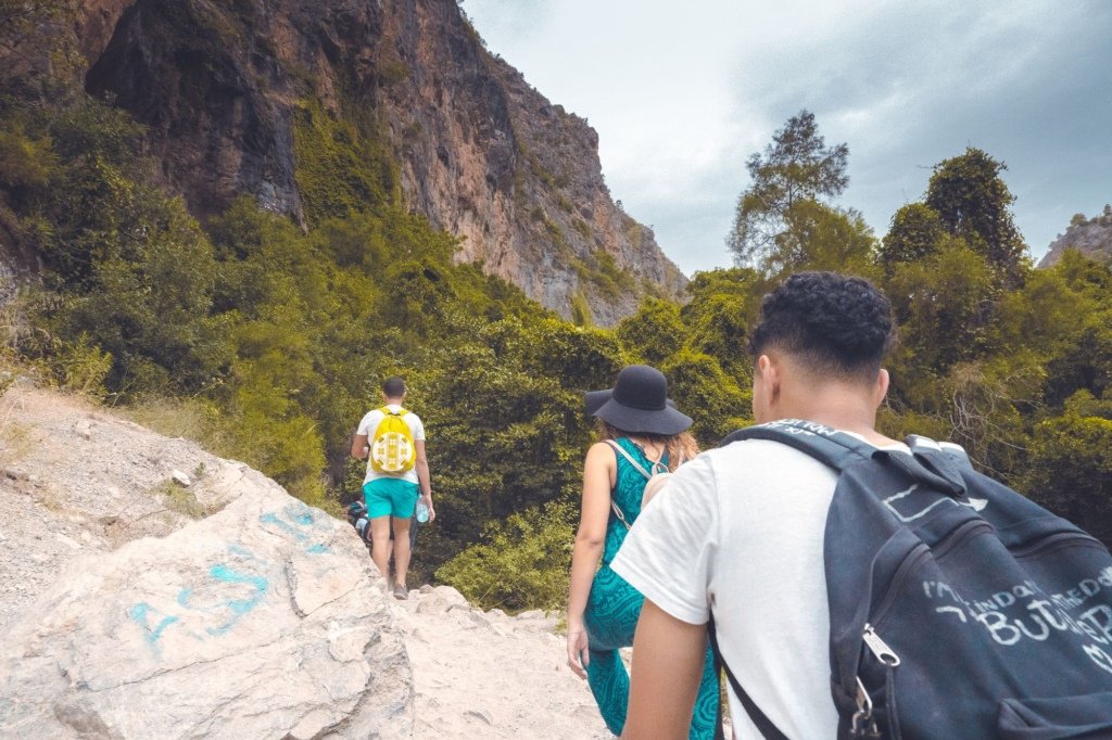 A group of hikers on a rocky trail through the green Akchour gorge in Morocco's Rif Mountains