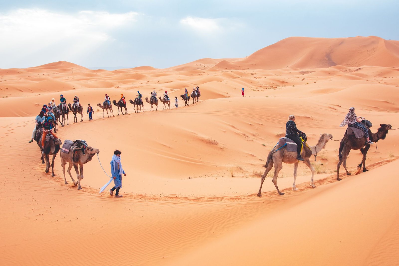 Travellers riding camels in a caravan across the Erg Chebbi sand dunes at Merzouga, Morocco