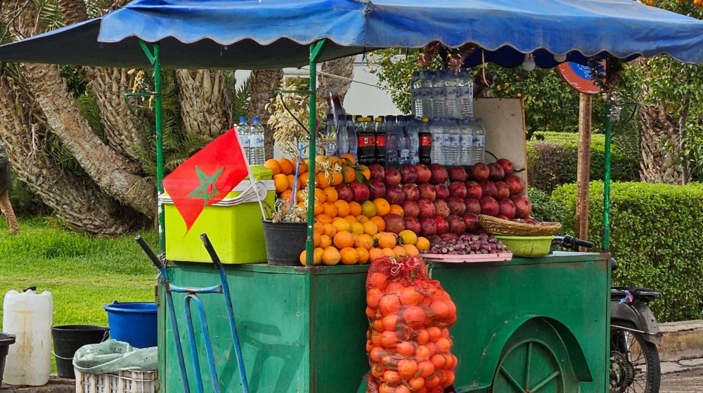An orange juice cart piled with fresh oranges on a street in Marrakech, Morocco