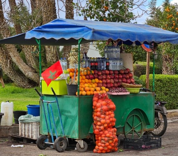 An orange juice cart piled with fresh oranges on a street in Marrakech, Morocco