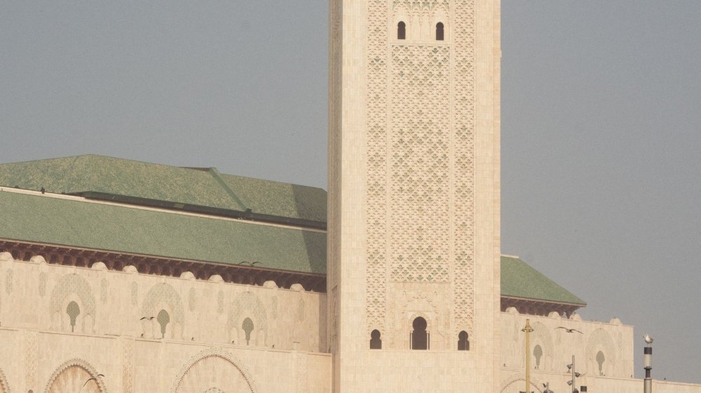 Visitors walking along the seafront esplanade in front of the Hassan II Mosque and its minaret in Casablanca