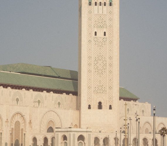 Visitors walking along the seafront esplanade in front of the Hassan II Mosque and its minaret in Casablanca