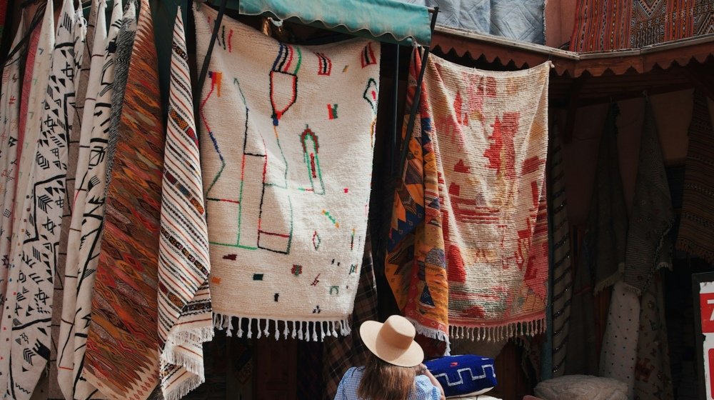 A woman in a sun hat browsing the goods outside a shop in the Marrakech souks