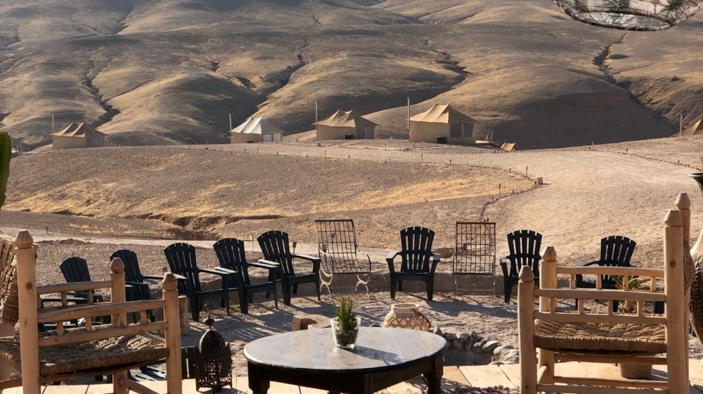 Wooden seating on a desert camp terrace overlooking the arid hills of the Agafay Desert
