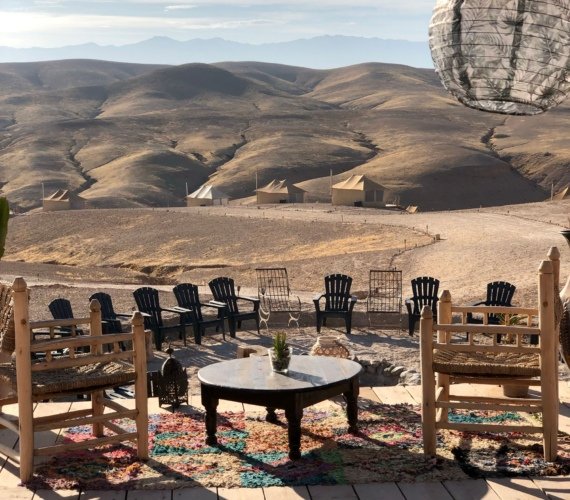 Wooden seating on a desert camp terrace overlooking the arid hills of the Agafay Desert