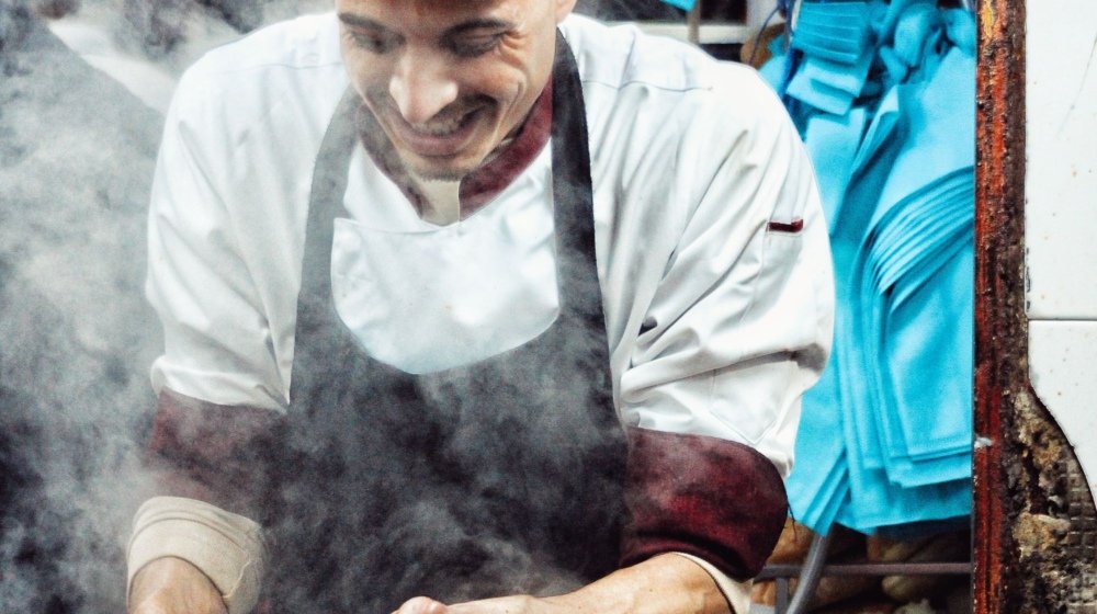 A street food vendor grilling spicy merguez sausages over hot coals at a market in Rabat, Morocco