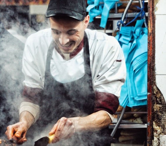 A street food vendor grilling spicy merguez sausages over hot coals at a market in Rabat, Morocco