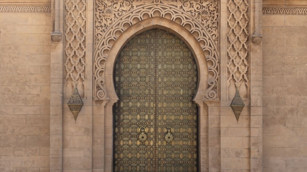 A visitor photographing the ornate carved gate of the Mausoleum of Mohammed V in Rabat, Morocco