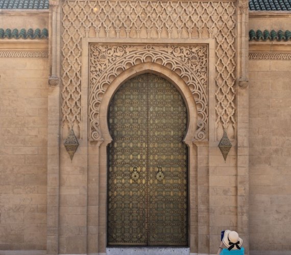 A visitor photographing the ornate carved gate of the Mausoleum of Mohammed V in Rabat, Morocco