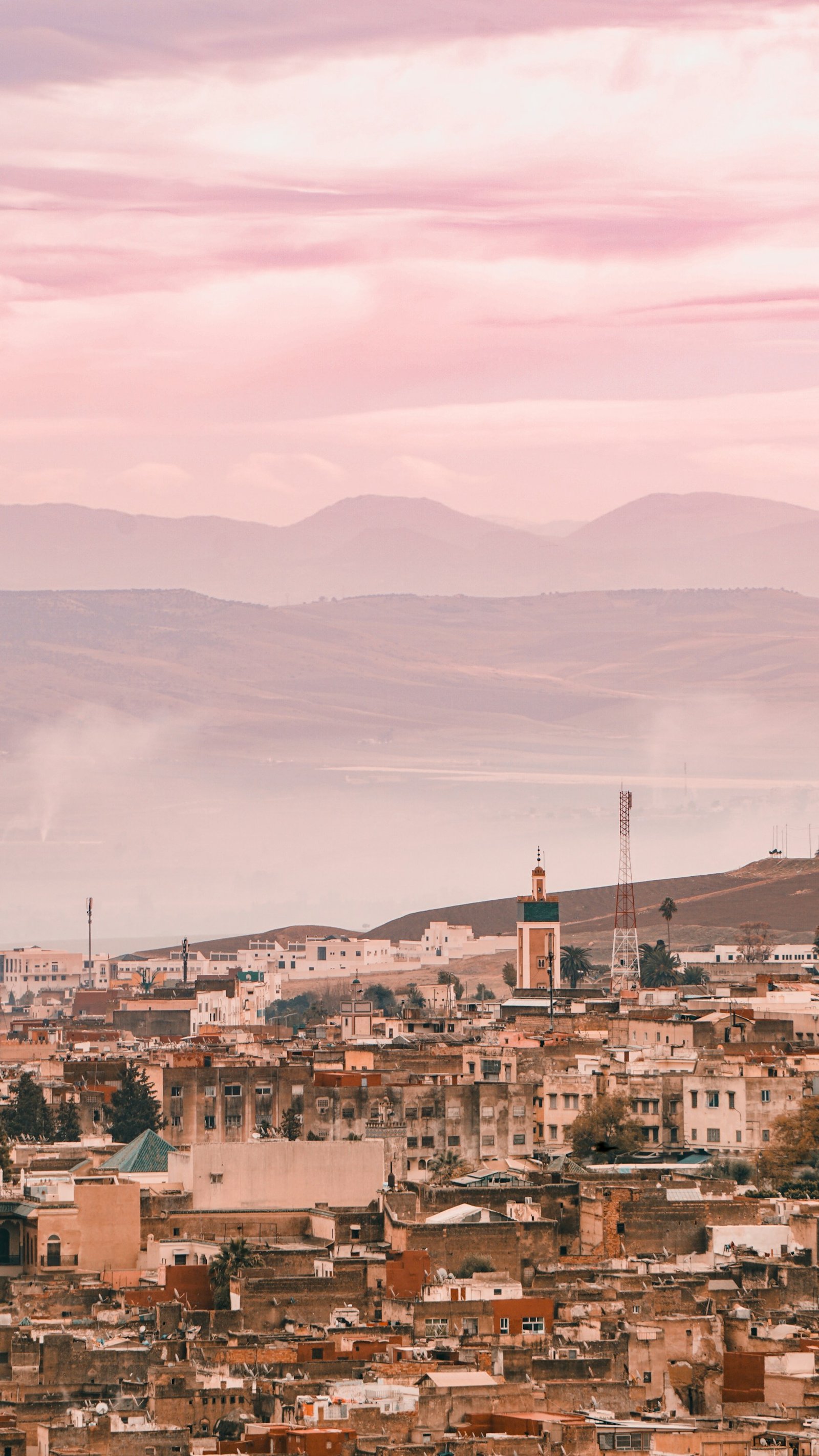 The rooftops of the Fes medina at dusk, a minaret rising above them
